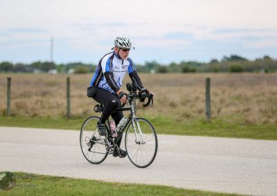 Comfortable senior cyclist riding a hybrid bike on a scenic rural trail in Texas.