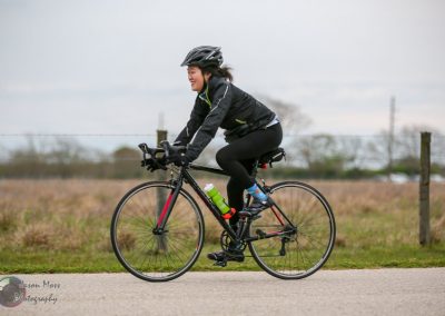 Vibrant woman cycling outdoors on a road bike during daytime, emphasizing healthy lifestyle and outdoor recreation.