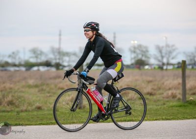 Bright woman cycling on scenic bike trail, promoting Bluebonnet Express for outdoor activities and fitness.