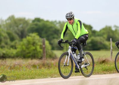 Bright yellow cycling jersey on male cyclist riding on scenic rural road for Bluebonnet Express event.