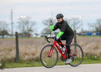 Vivid cyclist riding on a trail with a red bike, wearing a black and green cycling outfit and helmet.