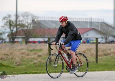 Young male cyclist riding on a paved trail in athletic gear for Bluebonnet Express bike event.