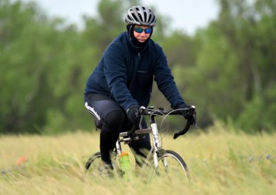 Vibrant cyclist riding through grassy field on Bluebonnet Express bike trail.