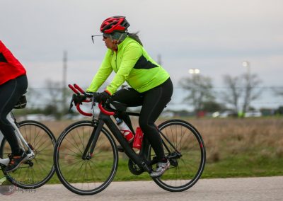 Vibrant cyclist in neon jacket riding a road bike during Bluebonnet Express event.