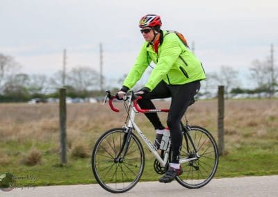 Bright green cycling jacket and helmet, cyclist enjoying a ride on the open road with scenic background.
