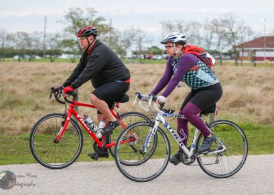 Vibrant cyclists riding bikes outdoors on a trail in a park, promoting Bluebonnet Express cycling tours.