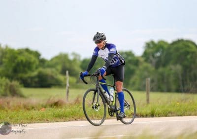 Bright blue and black cycling jersey worn by a cyclist riding along scenic country road.