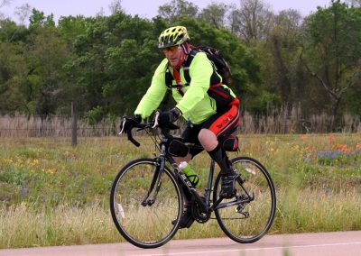 Vibrant cyclist riding a bike on scenic Texas trail during daytime.