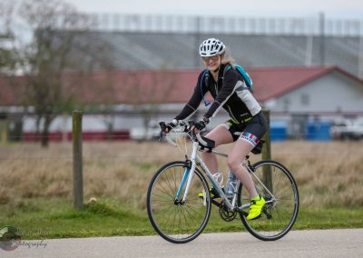 Bright female cyclist riding a bike on a scenic outdoor trail during daytime.
