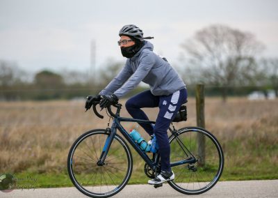 Mountaineer cyclist riding on a paved trail in a rural setting with a water bottle on bike frame.