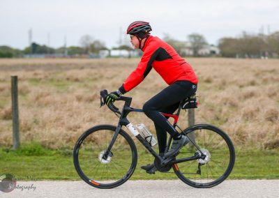 Vibrant cyclist riding Bluebonnet Express e-bike on scenic outdoor trail.