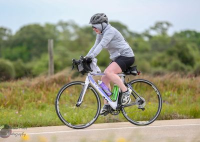 Vegan woman cyclist riding on a scenic trail during daytime, promoting eco-friendly transportation.