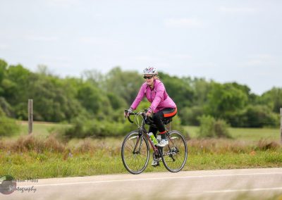 Vegan woman cycling on a rural trail with lush greenery in the background.