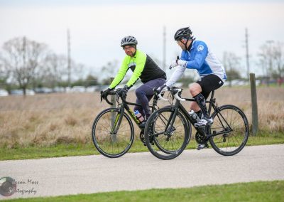 Brightly dressed cyclists riding on a scenic rural bike path during daytime.