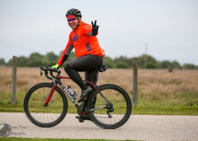Bright orange cycling jersey with "EMS" logo, riding a black and red Specialized bicycle outdoors.