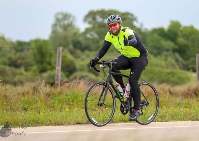 Bright yellow cycling jersey on man riding a Specialized road bike outdoors.