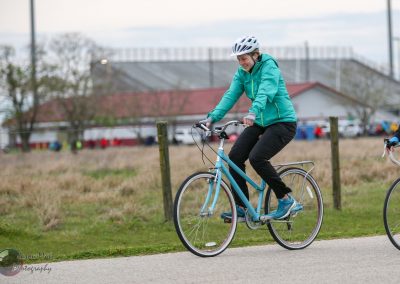 Bright blue bicycle on a scenic trail with a smiling woman in sporty attire.