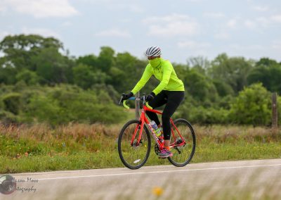 Bright yellow cycling jacket on woman riding a mountain bike on rural trail.