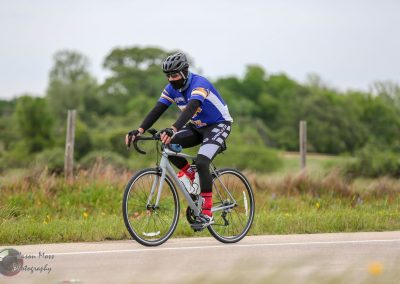 Bike riding on scenic rural road with green trees in background.