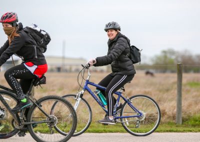 Comfortable women riding bicycles outdoor, promoting Bluebonnet Express bike services, eco-friendly transportation.
