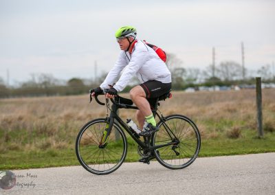 Man riding a bicycle outdoors in a natural setting, wearing a helmet and sports gear.