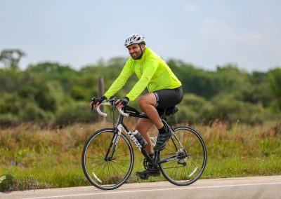 Bright yellow cycling jacket worn by man riding a bike on scenic rural road.