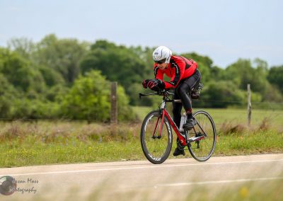 Vast: Cycling enthusiast riding a road bike outdoors on a lush rural trail with bluebonnets and green trees.