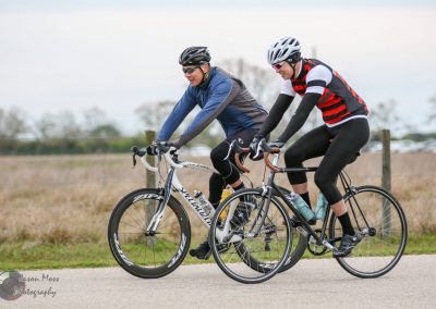 High-performance cyclists riding bikes on open road, Bluebonnet Express cycling event.