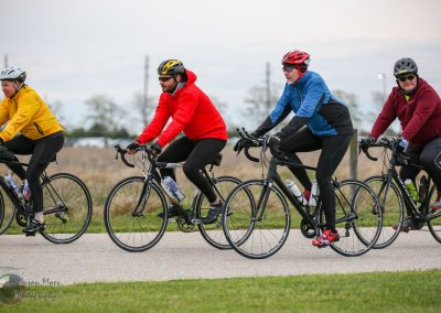 Brightly dressed cyclists enjoying a group ride on a suburban bike trail.