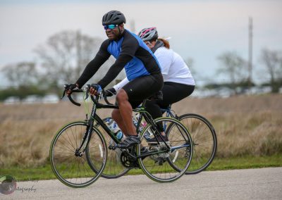 Brightly colored cyclists riding bikes outdoors on a cloudy day in Texas for Bluebonnet Express.