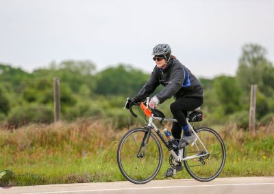 High-quality woman cyclist riding a bike on outdoor trail in rural landscape.