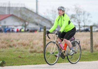 Bright yellow cycling jacket on woman riding e-bike, Bluebonnet Express, Texas scenic bike trail.