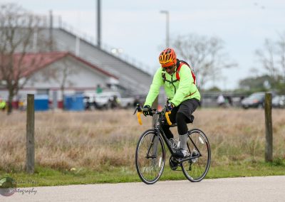 Bright neon green cycling jacket and helmet on a rider biking outdoors during daytime.