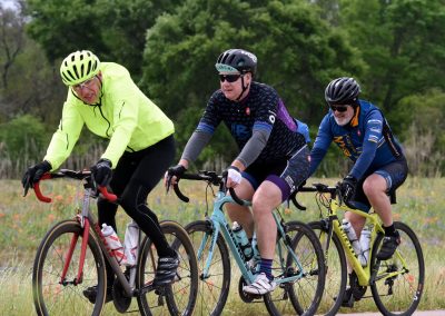 Brightly dressed cyclists riding through scenic countryside on a lively bike tour.