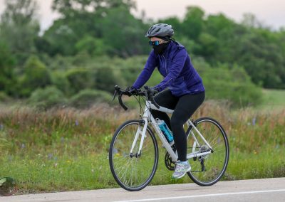 Comfortable woman riding a hybrid bike on scenic outdoor trail in natural setting.