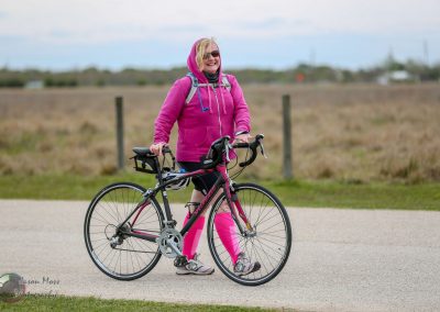 Bright pink and black specialized road bike with a woman in pink cycling outfit on a paved trail.