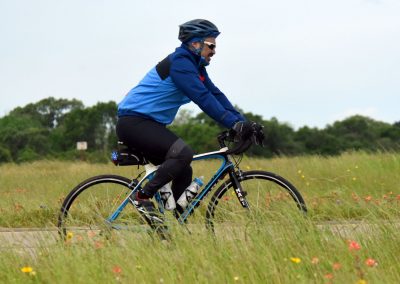 Vast outdoor scene with cyclist riding through a grassy field with wildflowers, promoting eco-friendly bike transport.