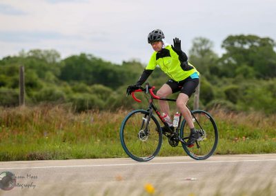 Vegan cyclist in neon yellow jacket riding on rural road during daytime.