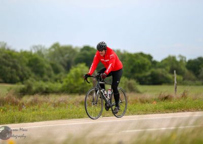 Energetic cyclist riding on rural road during daytime for Bluebonnet Express event.