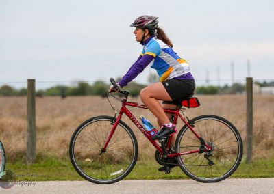 Colorful cyclist riding a hybrid bike on a scenic trail during daytime.