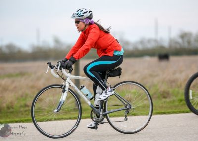 Vibrant female cyclist riding on a scenic rural trail with Bluebonnet Express bike.