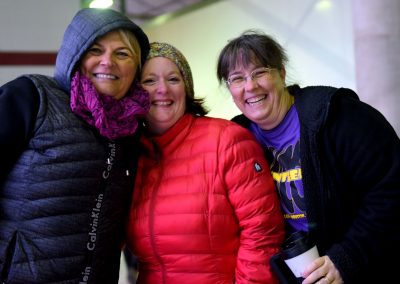 Smiling women wearing outdoor winter jackets at Bluebonnet Express event, showcasing community and outdoor adventure.