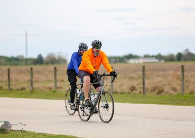 Brightly dressed cyclists riding e-bikes outdoors on a scenic trail.