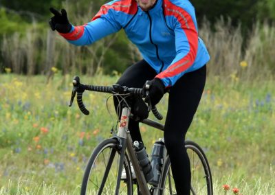 Bright smiling cyclist riding a bicycle in nature during daytime.