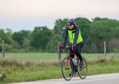 Bright green and black cycling jacket, cyclist riding a road bike outdoors during daytime for Bluebonnet Express.