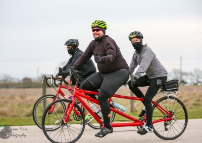 Smiling couple riding a tandem bike during outdoor cycling event, promoting Bluebonnet Express service.