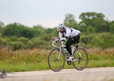 High-performance cyclist riding a Focus road bike on scenic outdoor trail, promoting Bluebonnet Express bike tours.
