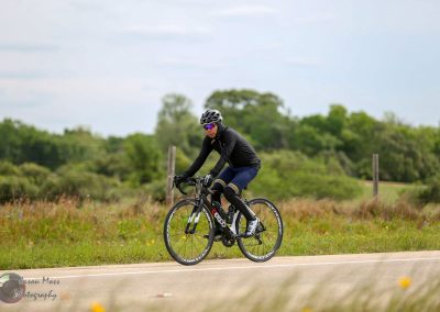 High-performance cyclist riding on scenic rural road in outdoor sports gear.