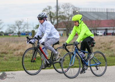 Helmeted kids riding bikes outdoors on a cloudy day, enjoying cycling at Bluebonnet Express race.