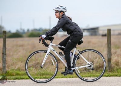 Bike riding on a paved trail near open fields in casual athletic gear.